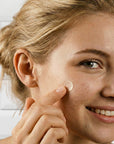 Woman applying pimple hydrocolloid patch to her face with a white background