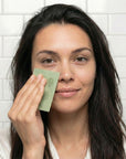 Woman using oil blotting paper in a bathroom setting